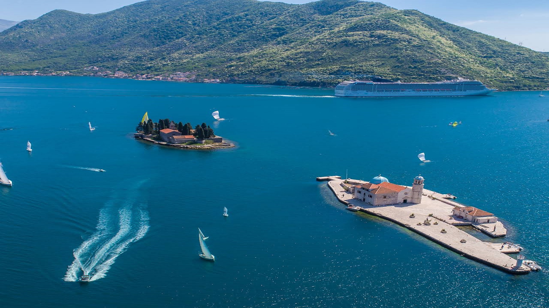 Aerial view of Our Lady of the Rocks and St George island with a cruise ship in the bay