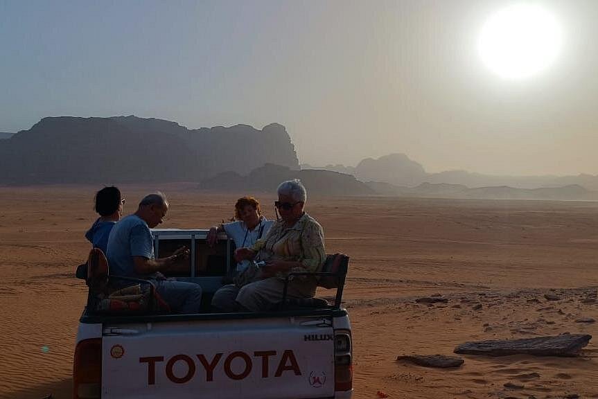 Private tour guests riding in a four-wheel-drive vehicle at sunset in Wadi Rum