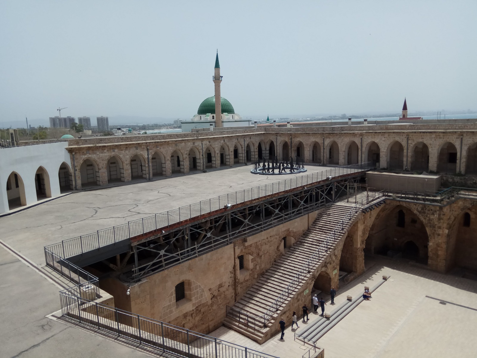 Overhead view of the expansive stone courtyard and arched walkways near the green-domed mosque