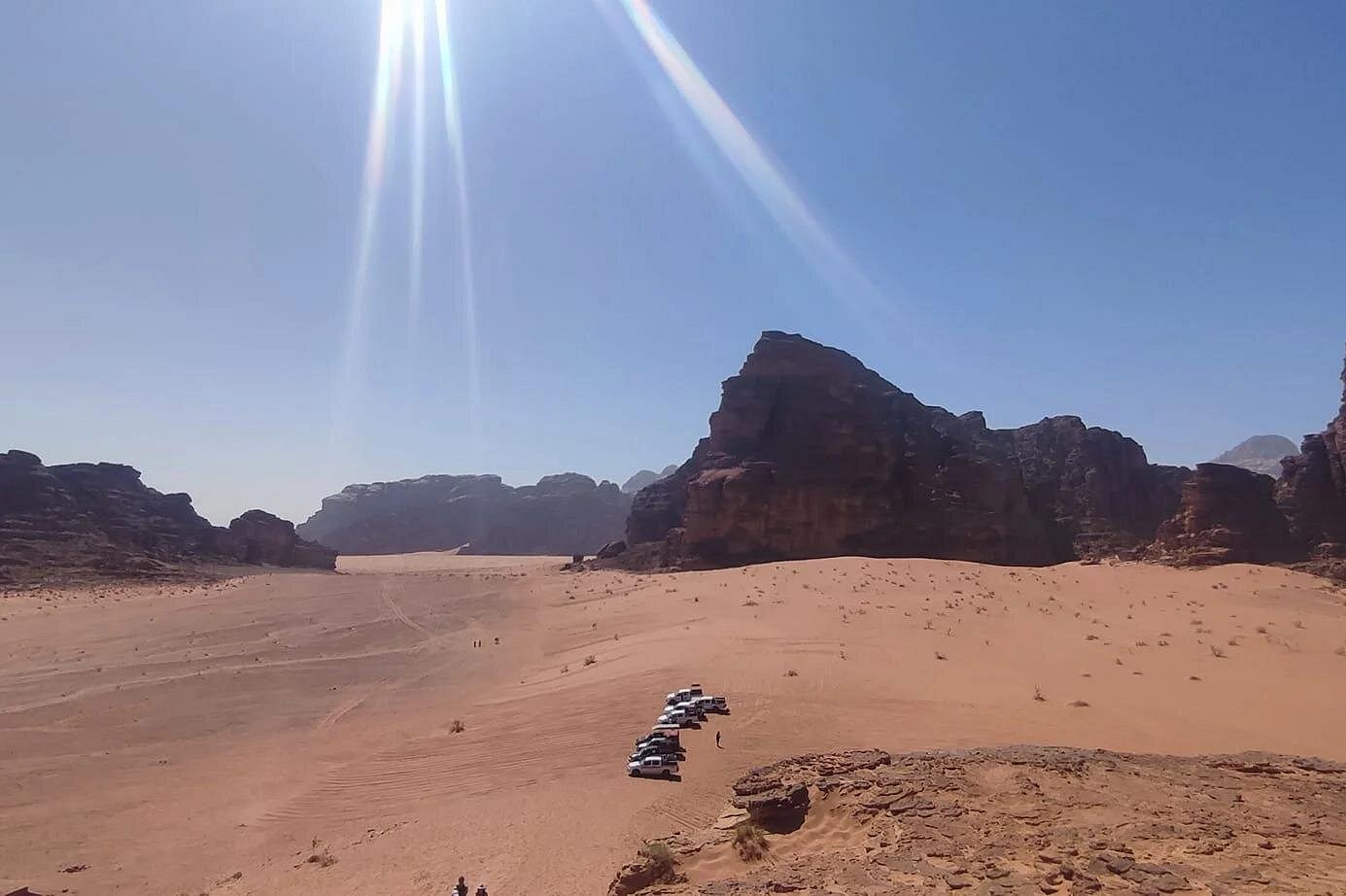 Four-wheel-drive vehicles beneath towering sandstone cliffs in Wadi Rum