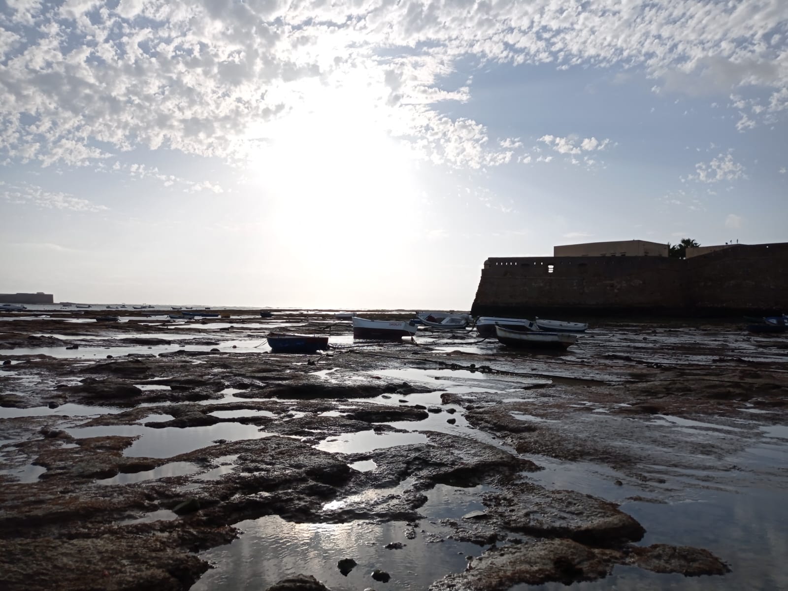 La Caleta beach at low tide with fishing boats and the sea wall