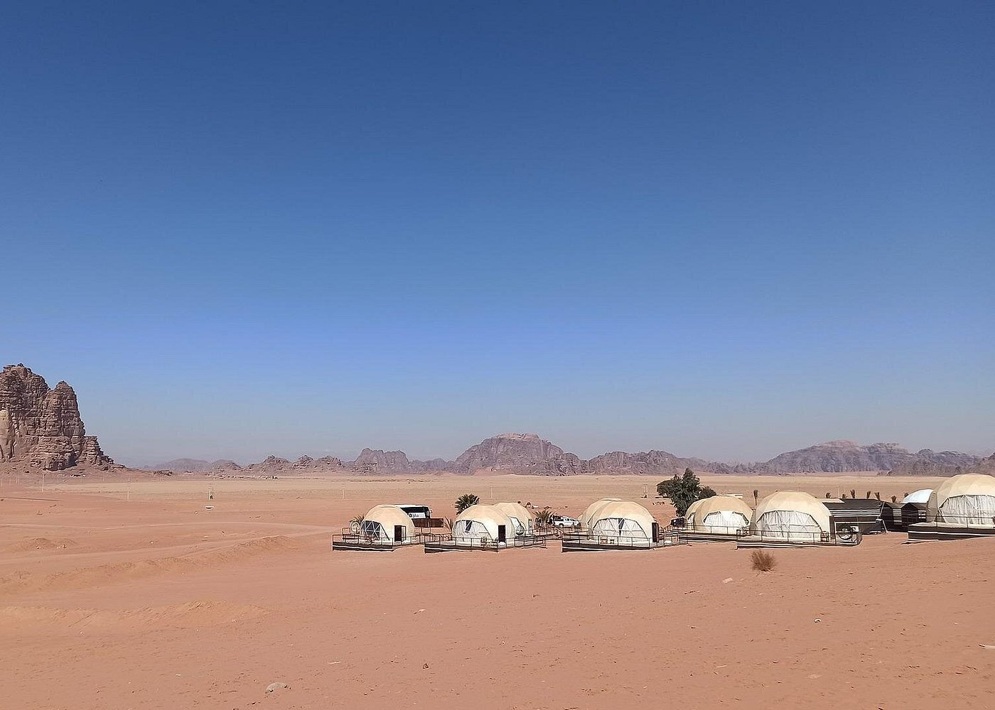 Panoramic desert camp with white dome tents across Wadi Rum