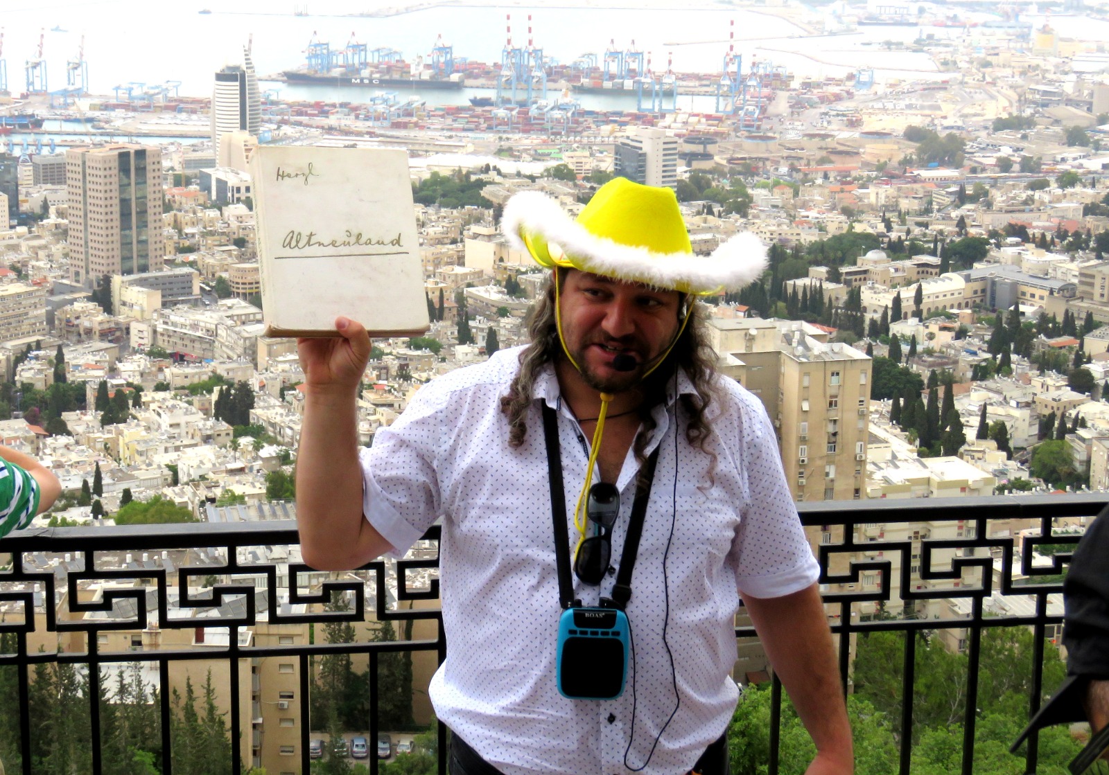 Guide in a yellow hat overlooking the Port of Haifa and the Bay of Haifa from Louis Promenade