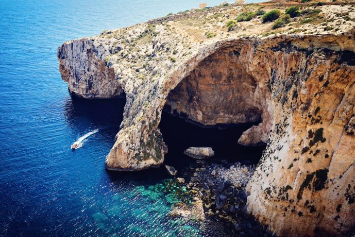 Malta's Blue Grotto sea caves with a boat on turquoise water