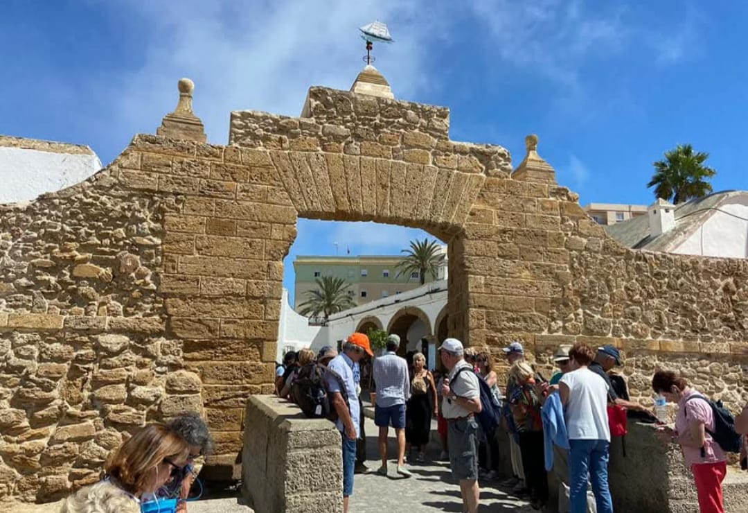 Tourists walking through a historic stone archway in Cadiz