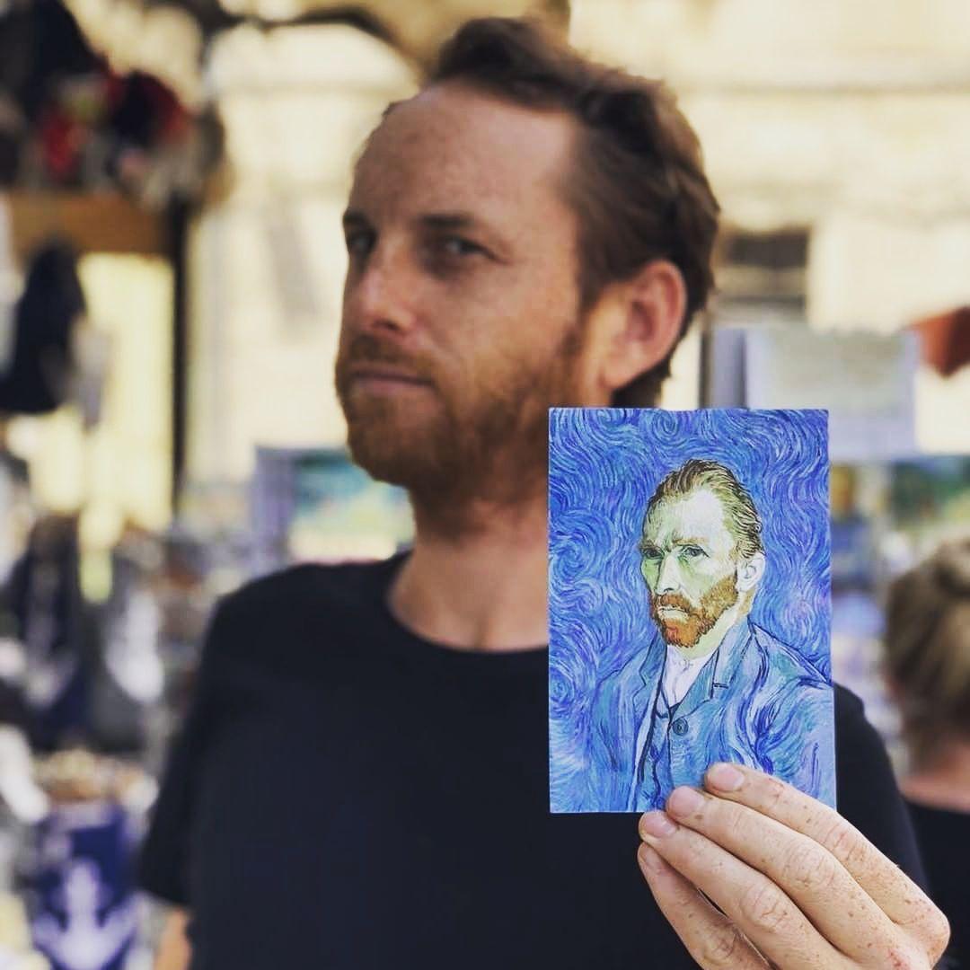 Guide holding a Van Gogh self-portrait postcard in a Provencal market