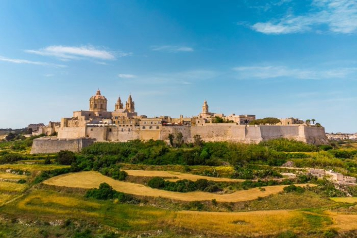 The fortified walls of Mdina, Malta, above green countryside
