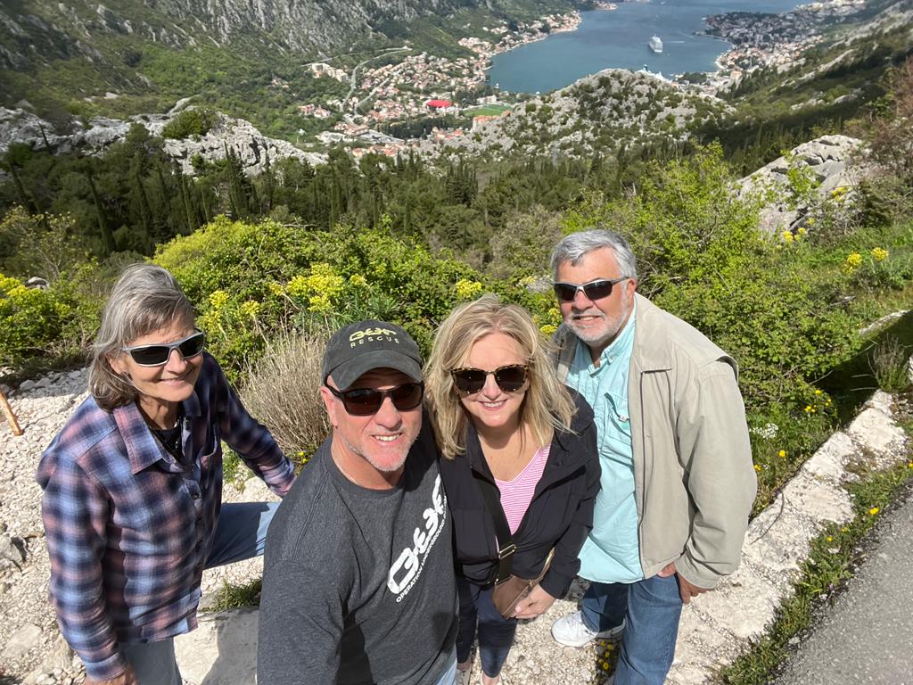 Travelers smiling at a mountain viewpoint above the Bay of Kotor, Montenegro